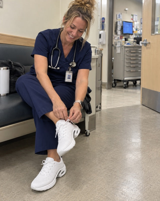 A nurse lacing the white shoes on a hospital ward
