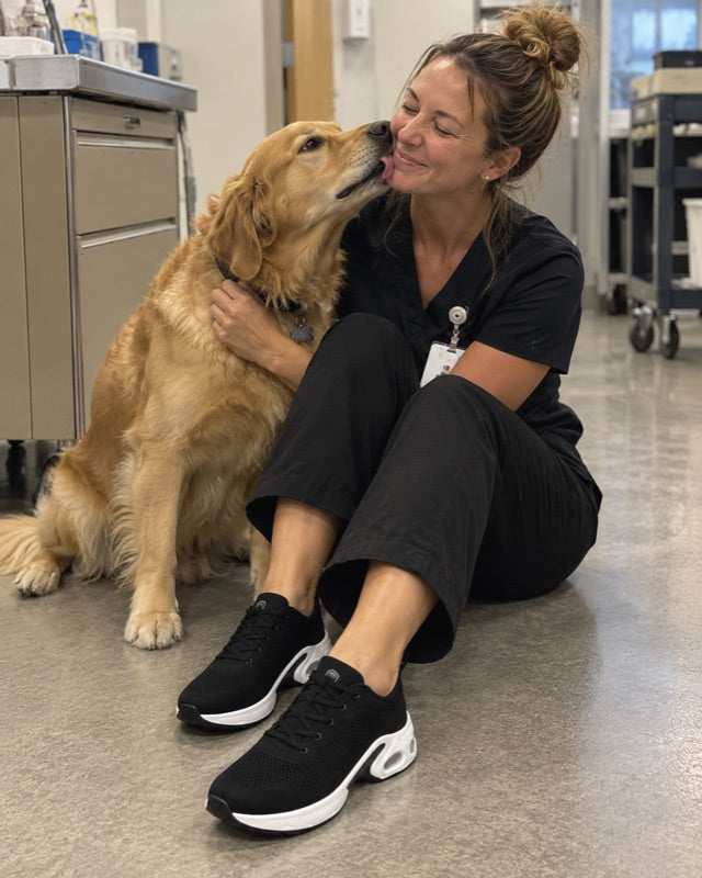 A nurse sitting on the ward floor with a golden retriever